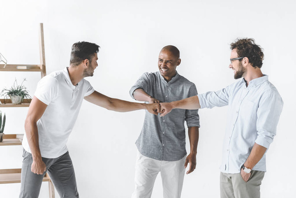 monikansallinen ryhmä nuoria liikemiehiä, jotka pitävät toisiaan kädestä
 - Valokuva, kuva