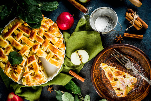 Traditional autumn baking, homemade apple pie with cinnamon, dark blue background with rolling roll, sugar powder, fresh apples, spices, copy space top view - Photo, Image