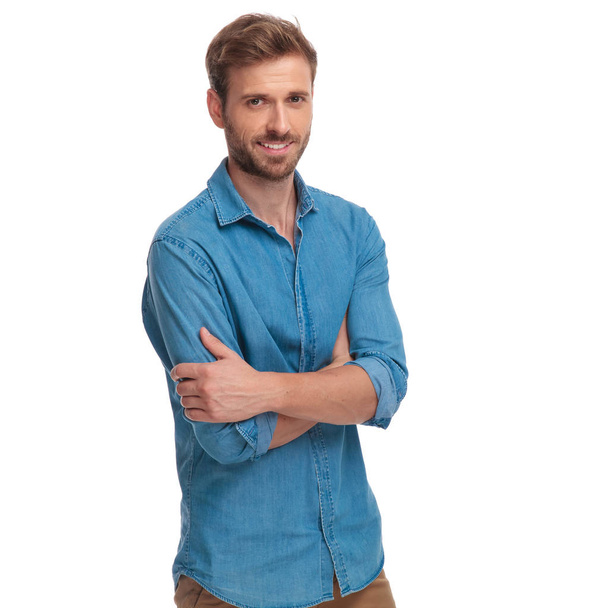confiante jovem homem casual com os braços dobrados, sorrindo no fundo branco
 - Foto, Imagem