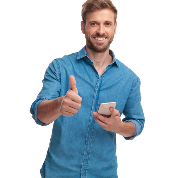 χαρούμενος περιστασιακή άνθρωπος ανάγνωση καλές ειδήσεις του τηλεφώνου και κάνει εντάξει σύμβολο σε άσπρο φόντο - Φωτογραφία, εικόνα