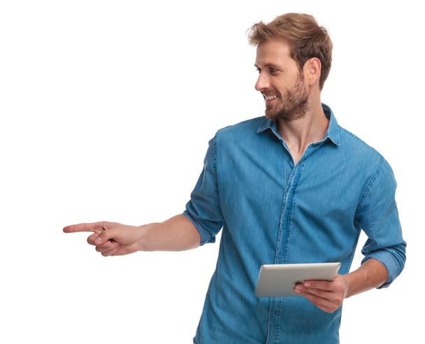 joven hombre casual sosteniendo puntos tableta dedo a lado sobre fondo blanco
 - Foto, imagen