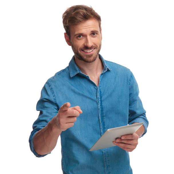 smiling student pointing finger while holding tablet on white background - Foto, imagen