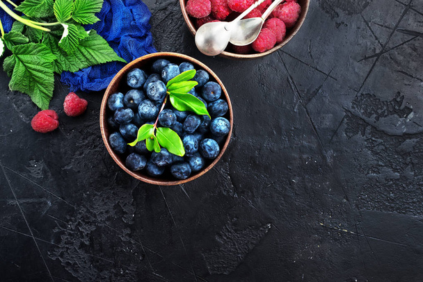 top view fresh blueberries and raspberries in wooden bowls served on table - Photo, Image