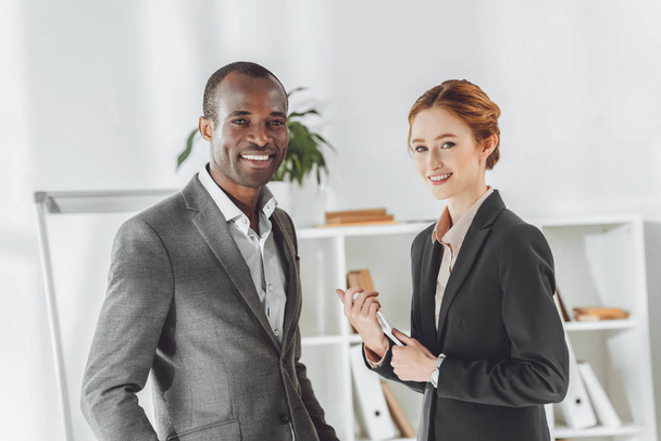 smiling african american businessman and caucasian businesswoman looking at camera - Фото, зображення