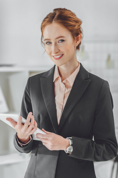 smiling businesswoman holding tablet and looking at camera - Photo, image