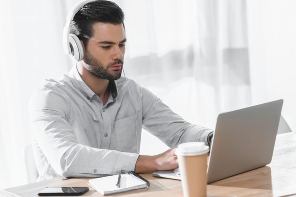 handsome businessman listening music and working at laptop - Фото, изображение