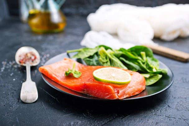salmon steak with lime slice and fresh spinach served on plate - Foto, Imagem