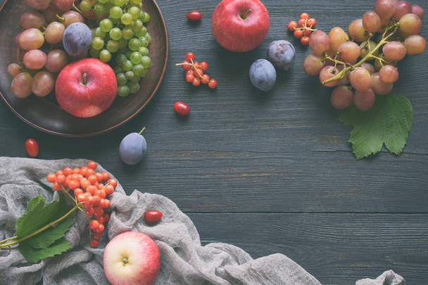 Syksyn asetelma kiitospäivänä syksyn hedelmillä ja marjoilla puupohjalla rypäleet, omenat, luumut, viburnum, koiruoho. Raakaa ruokaa. Kopioi tila
. - Valokuva, kuva