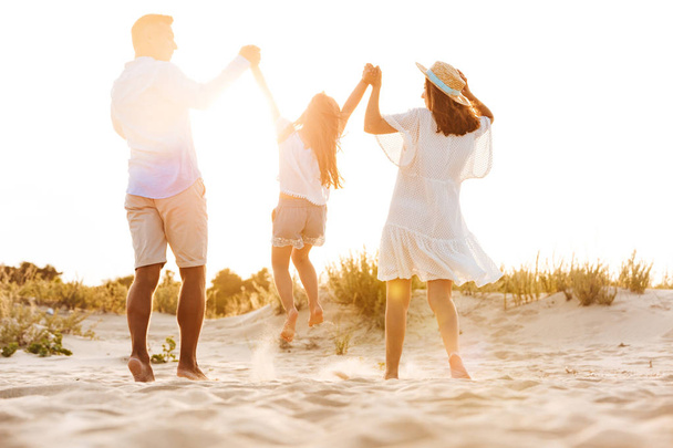 Photo of young cute happy family having fun together outdoors at the beach. - 写真・画像