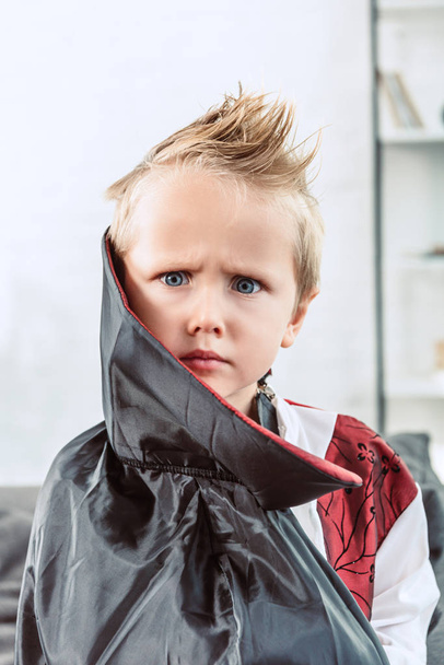portrait of little boy in vampire halloween costume looking at camera at home - Foto, immagini