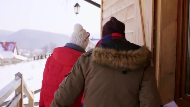 Rear view of couple leaving a chalet in the mountains - Záběry, video