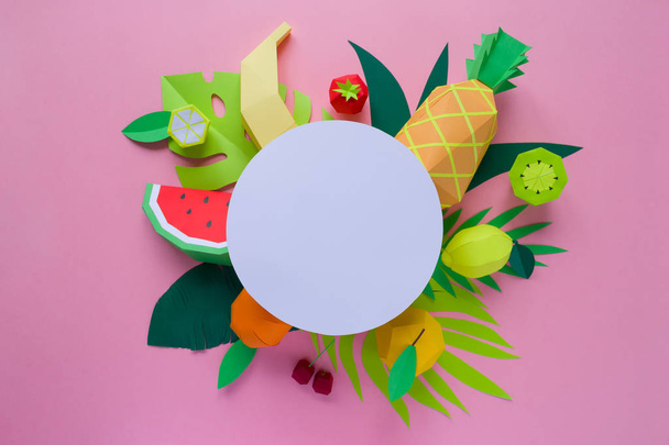 Round frame with exotic fruits with different tropical leaves made of paper on pink background - Foto, Imagen