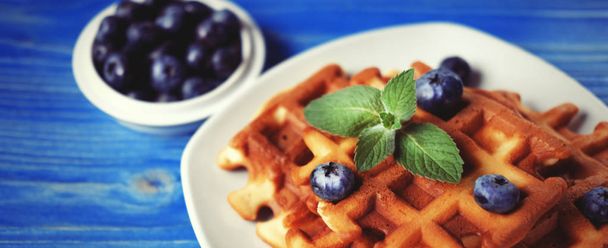 Homemade belgian waffles with fresh blueberry and raspberry over wooden background. Top view. - Foto, afbeelding