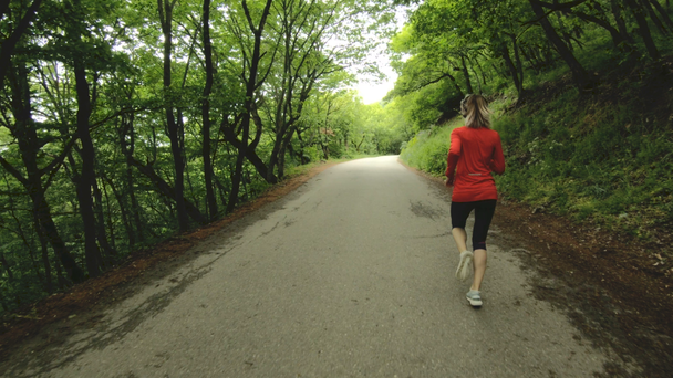 Juokseva tyttö. Blondi tyttö tekee ulkona urheilua kesällä metsässä. Taustakuva hidastettu laajakulma
 - Materiaali, video