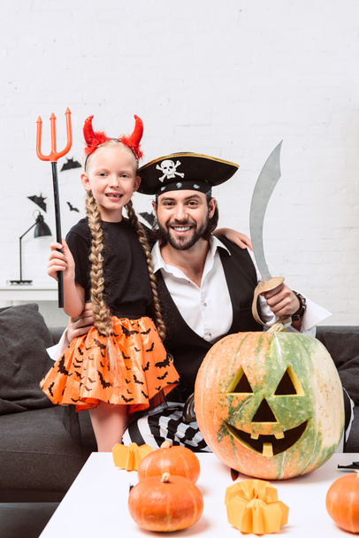 happy daughter and father in halloween costumes at home - Valokuva, kuva