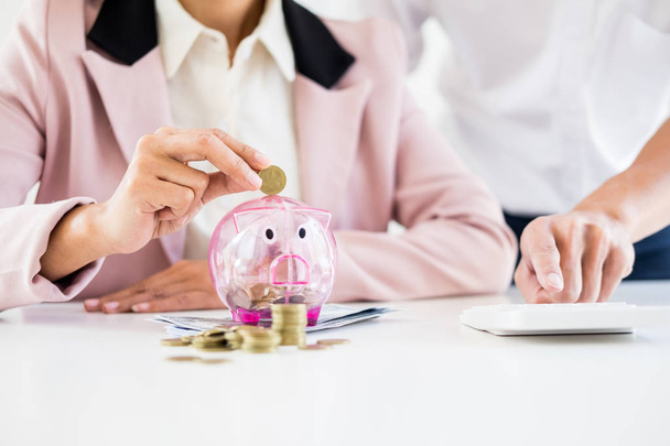 Close-up de Empresário colocando moeda em pequeno banco porquinho, O conceito de poupar dinheiro e investimento
. - Foto, Imagem