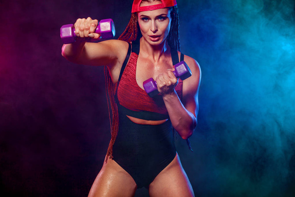 Attractive young fitness woman holding dumbell. Studio shot. - Φωτογραφία, εικόνα