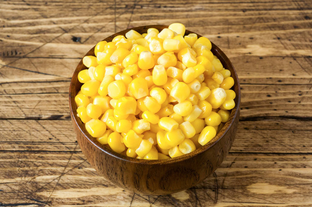 Canned corn in wooden plate on rustic wooden background. - Valokuva, kuva