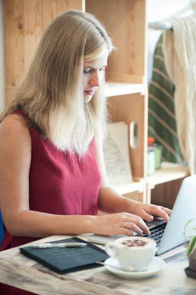Young blonde woman freelancer typing in laptop in cafe - Photo, Image