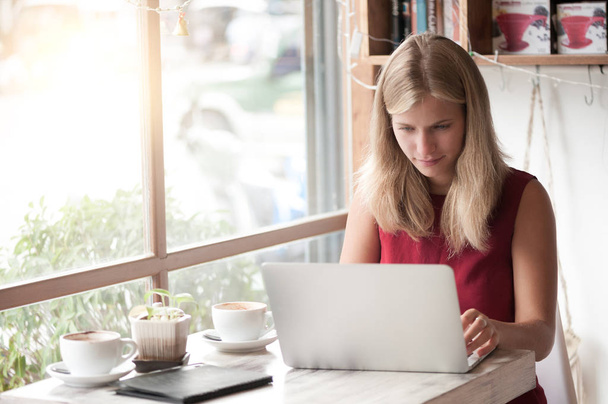 Young blonde woman freelancer typing in laptop in cafe - Photo, image