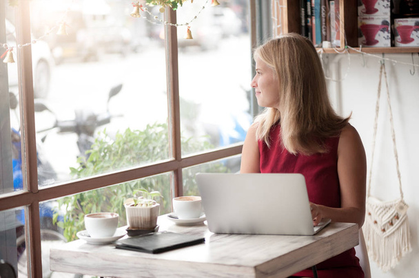 Young blonde woman freelancer typing in laptop in cafe - Photo, Image