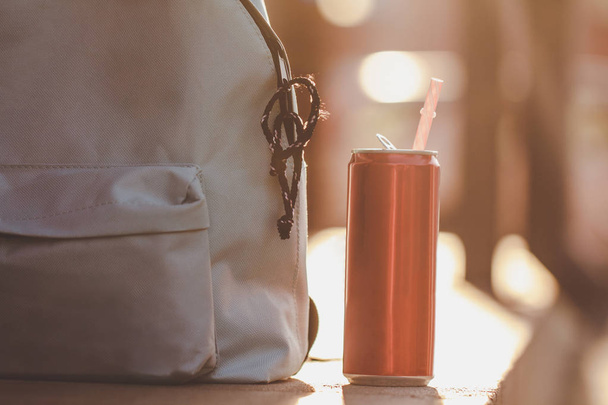 Blue backpack with cocktail from cola on sunset background - 写真・画像