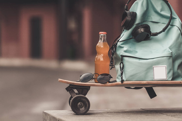 Blue backpack standing on long board with headsets and bottle with beverage  - Foto, Bild