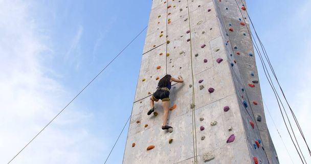 Mulher alpinista de pedra se exercitando na parede do ginásio de escalada ao ar livre
 - Foto, Imagem