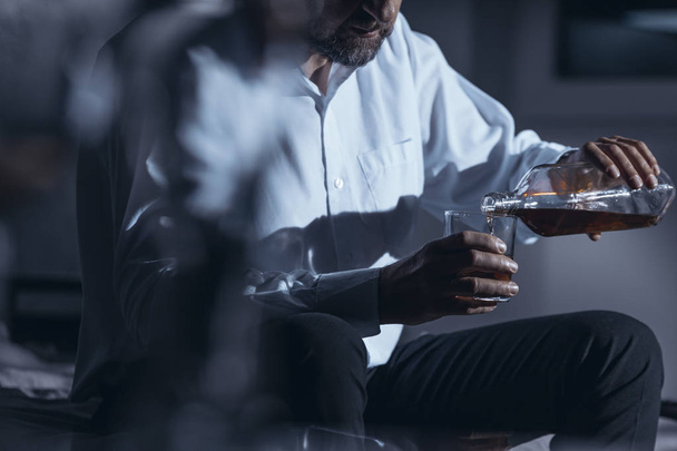 Zbliżenie: przygnębiony biznesmen picia alkoholu podczas siedzi sama w domu - Zdjęcie, obraz