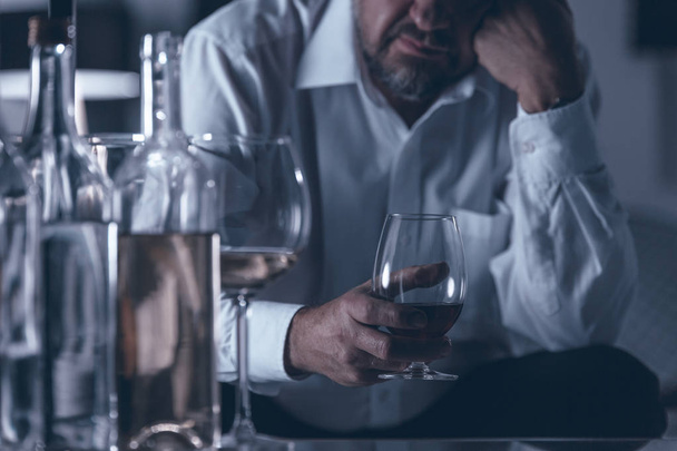 Close-up of sad and lonely alcoholic drinking wine in a dark room - Фото, зображення