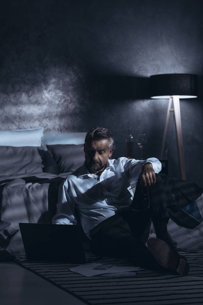 Lonely businessman working at home in the dark. Concept of a workaholic - Zdjęcie, obraz
