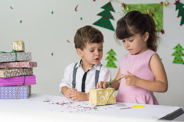 Cute happy excited children, boy and girl open christmas present box in beautiful room. Sister and brother give Xmas gifts near decorated tree. Family holiday - Fotografie, Obrázek