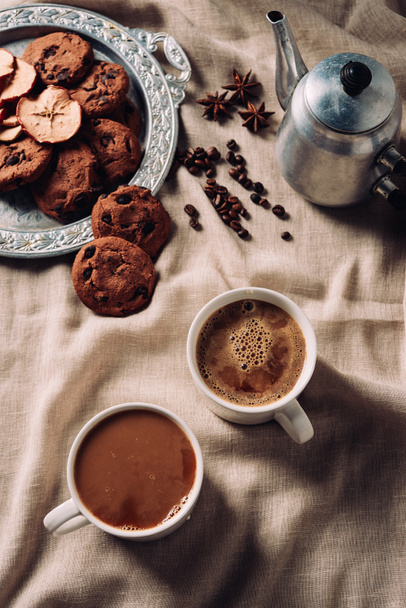 felülnézete a bézs ruhával csésze friss kávé és csokoládé chip cookie-kat és a vintage fém pot - Fotó, kép