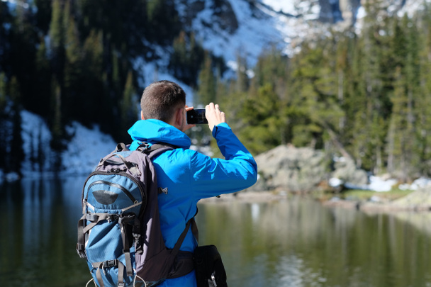 Wandelaar toeristische met rugzak nemen van foto met smartphone in de buurt van Bear Lake op herfst in Rocky Mountain National Park. Colorado, Usa.  - Foto, afbeelding