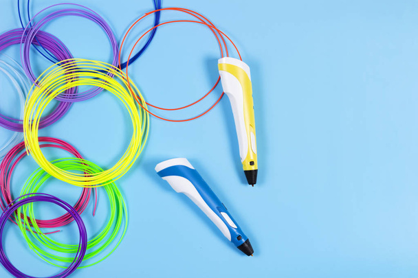 3d pens with colourful plastic filament on blue background - Foto, afbeelding