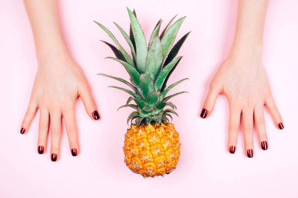 Red manicure on pink background with pineapple - 写真・画像