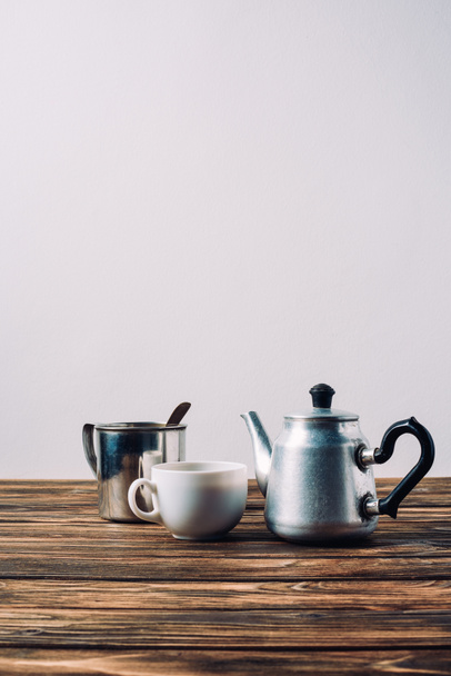 various cups of coffee with vintage metal pot on rustic wooden table - Foto, afbeelding