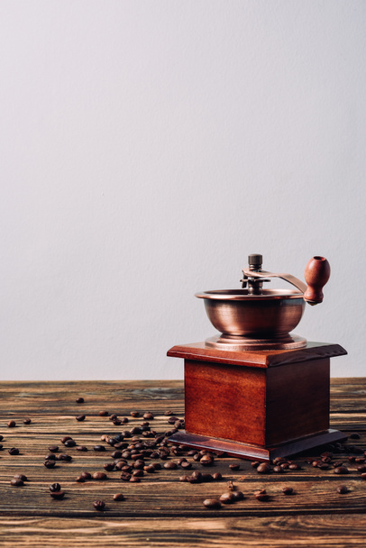 vintage coffee grinder with coffee beans on rustic wooden table - Фото, изображение
