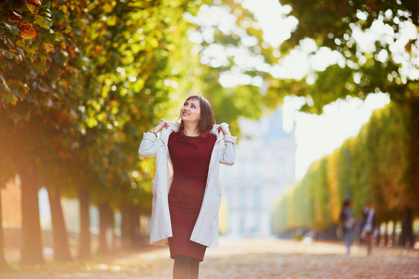 Beautiful young woman in Paris walking in park on a bright fall day. Tourism and vacation in France at autumn season - Фото, изображение