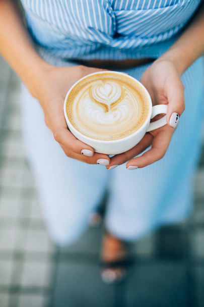 Woman holding cup of cappuccino with latte art - Photo, Image