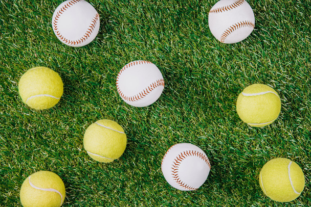плоска лежала з розташуванням тенісних і бейсбольних м'ячів на зеленій траві
 - Фото, зображення