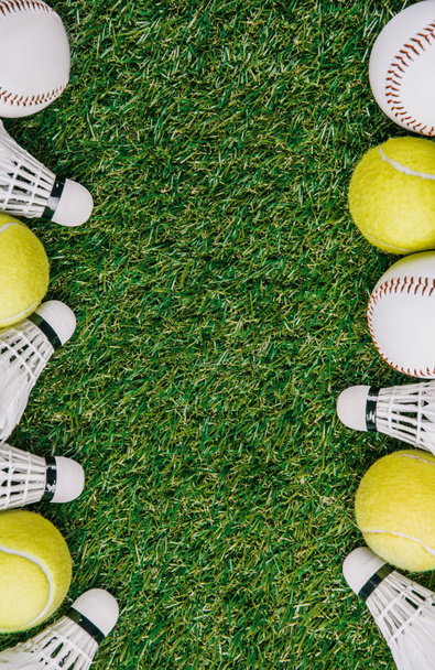 top view of arrangement of badminton shuttlecocks, tennis and baseball balls on green lawn - Foto, Imagen