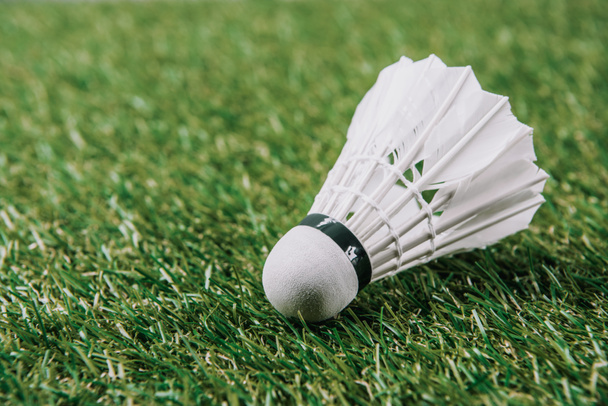 close up view of white shuttlecock lying on green lawn - Foto, Imagen
