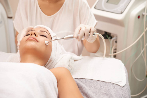 Young client of spa salon having relaxing procedure for facial skin rejuvenation - Photo, Image