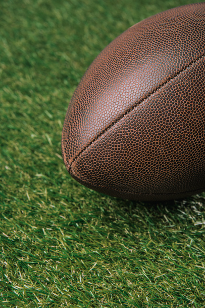 zblízka pohled kůže rugby míč ležící na zelené trávě - Fotografie, Obrázek