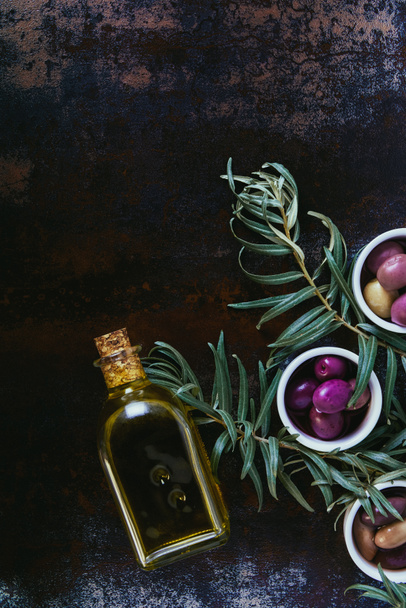 elevated view of different yummy olives and bottle of oil on shabby surface - Photo, Image