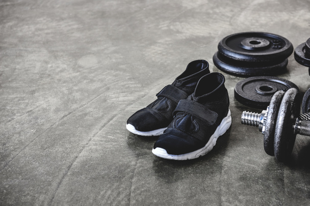 close-up shot of weight plates and sneakers on concrete floor - Foto, immagini