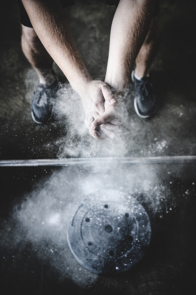 cropped shot of power lifter clapping hands with talc before training - Photo, Image