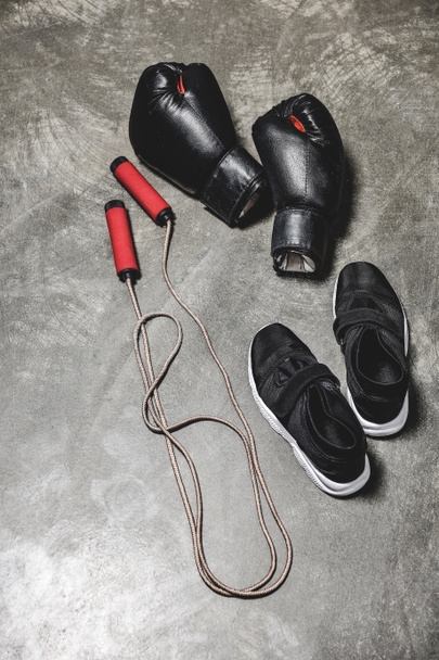sporting shoes with jumping rope and boxing gloves on concrete surface - Foto, immagini