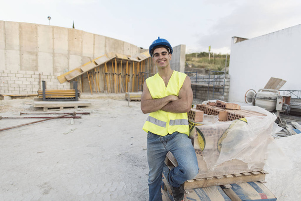 Улыбающийся строитель позирует для фотографии на рабочем месте
 - Фото, изображение